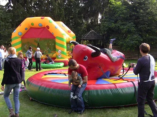 Dmuchana zjeżdżalnia i byk rodeo rozstawione na trawie