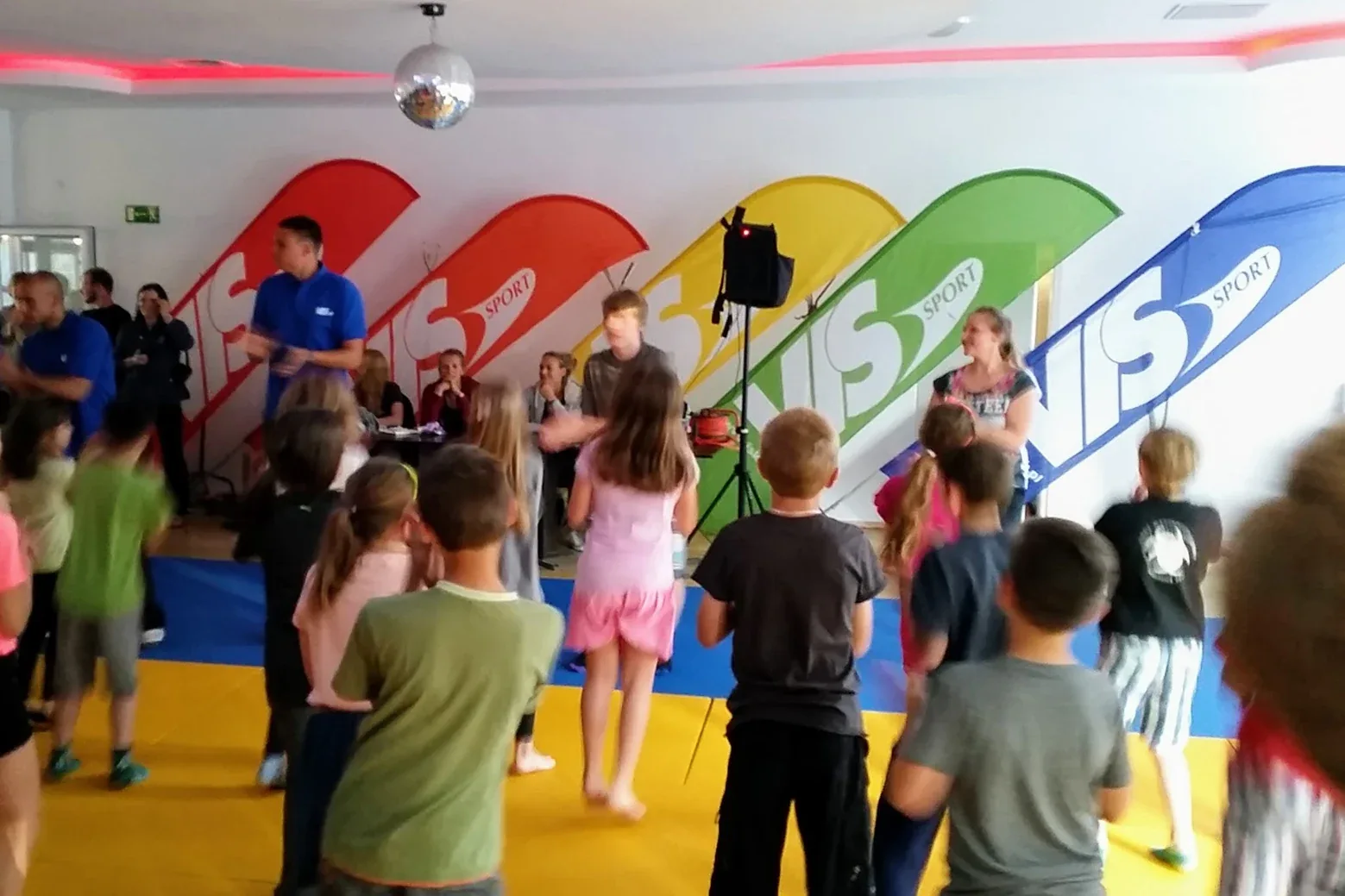 Wieczorna zabawa w sali ośrodka, na ścianie logo VIS Sport