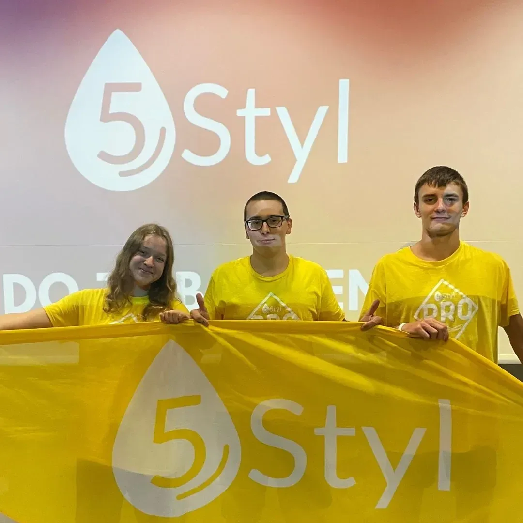 Troje uczestników w żółtych koszulkach rozciąga flagę 5Styl