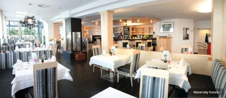 Hotelowa restauracja z nakrytymi stołami i kominkiem