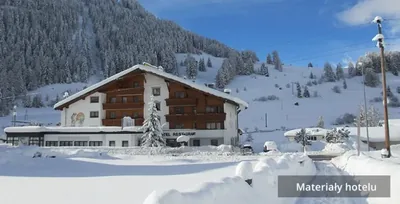 Hotel Bergblick w zaspach, za nim zalesione zbocze