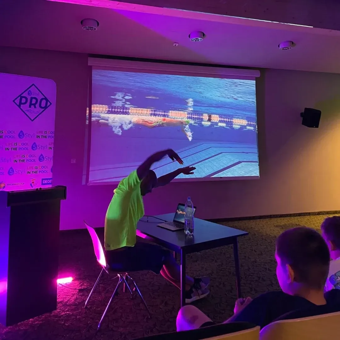 Trener przy laptopie omawia nagranie z toru wyświetlone na ekranie podczas video analizy