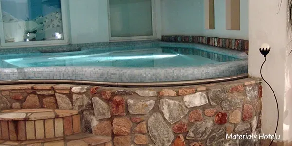 Basen z hydromasażem w kamiennej obudowie w hotelowym spa