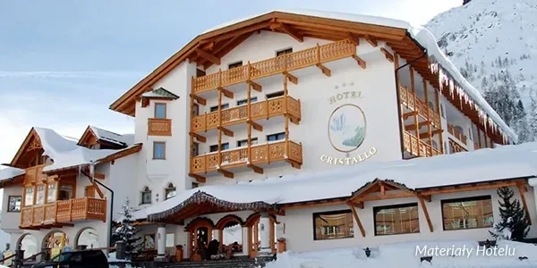 Ośnieżony Hotel Cristallo z drewnianymi balkonami u stóp stoku
