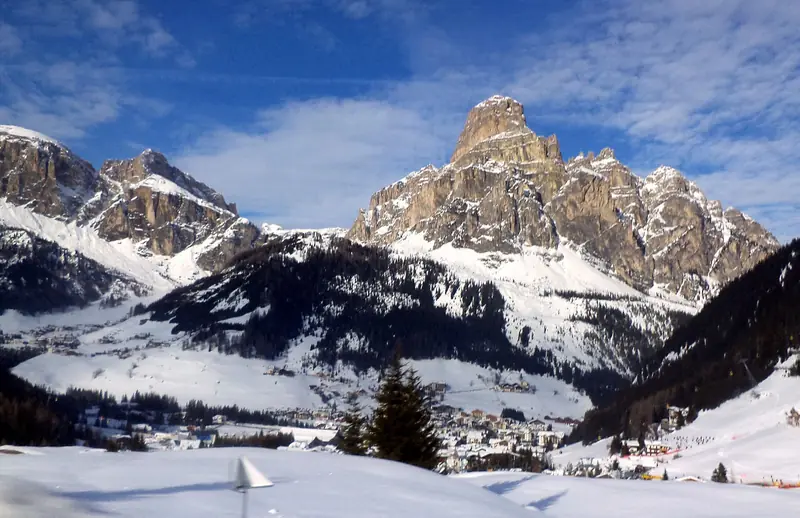 The snowy Corvara valley in Alta Badia, the Sassongher rock tower above it in the sun