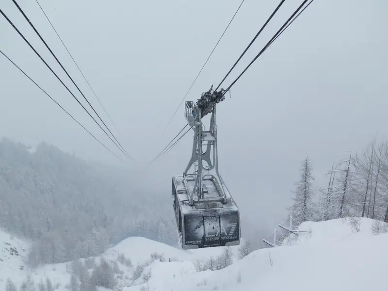 Kabina kolejki w Courmayeur w gęstym śniegu, oszroniony las w tle