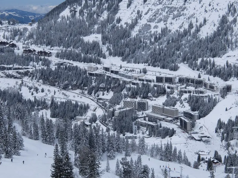 A winter view of Flaine's modernist buildings in their bowl above the valley, slopes and forest around