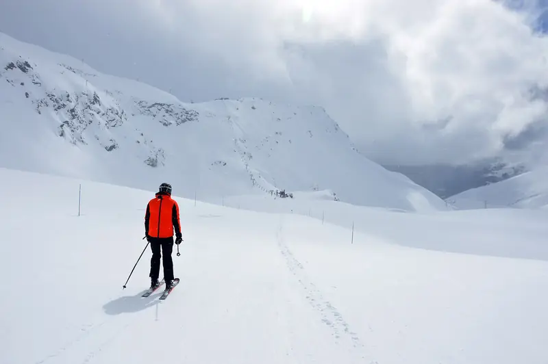 A skier on the open, snow-covered Faisan slope at La Rosière, snowy peaks and cloud over the ridge