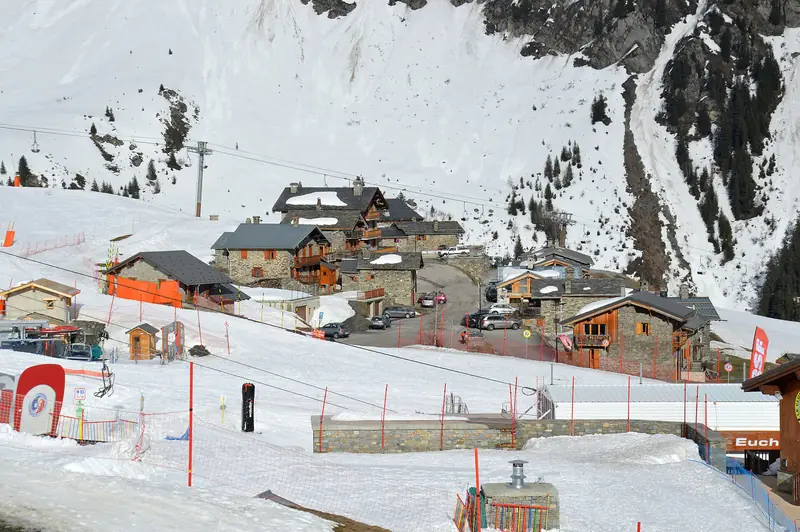 The snow-covered village of Les Eucherts at La Rosière in the evening: timber buildings and the ski school at the foot of the slope