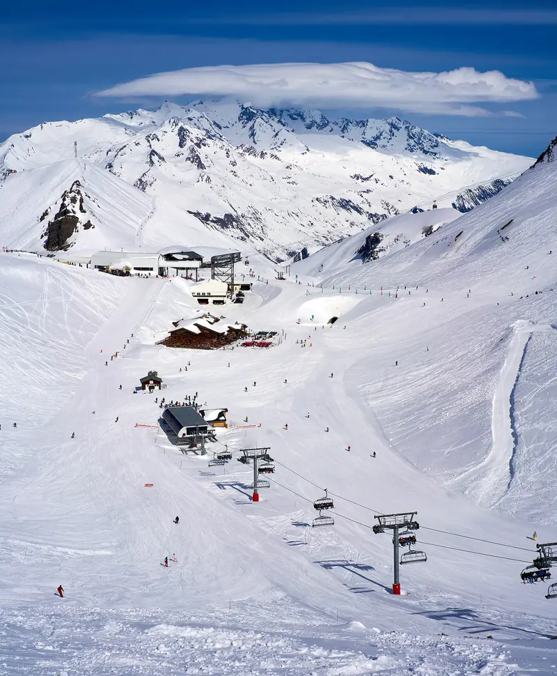 The high ski fields of Les Deux Alpes with lift lines and a station, steep snow-covered peaks behind