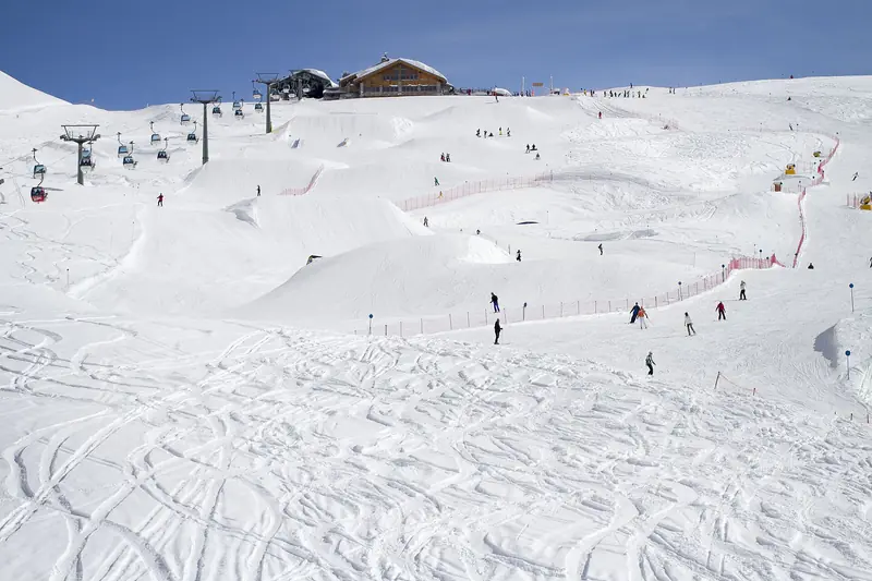 A broad groomed piste with skiers at Madonna di Campiglio, the Brenta Dolomites behind