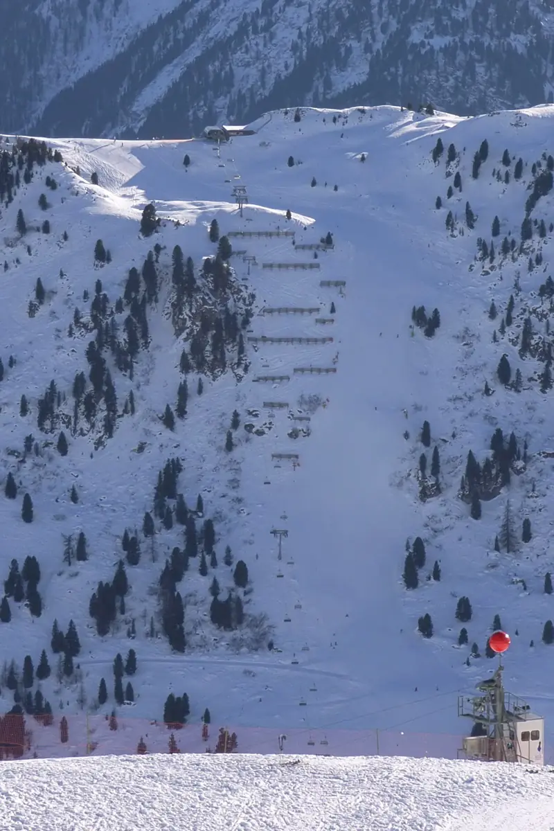 The steep snowy Harakiri piste at Mayrhofen among the firs, gates and skiers below