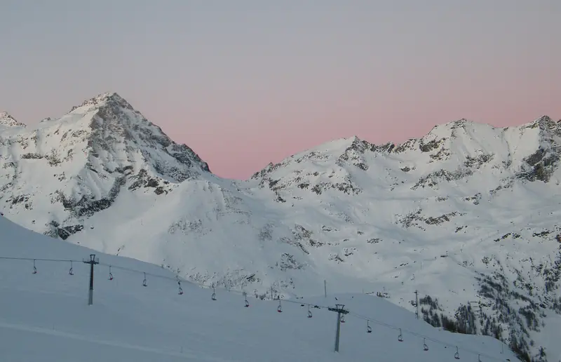 The snowy pistes and lifts of Monterosa Ski at dawn, a pink sky over the peaks