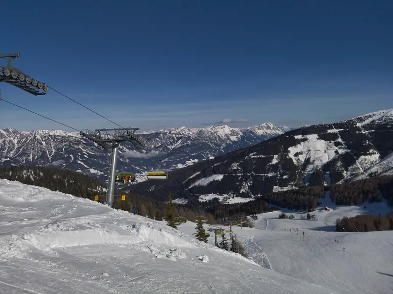 Kolej krzesełkowa nad wyratrakowanymi trasami Planai w Schladming, w dole dolina i ośnieżone szczyty