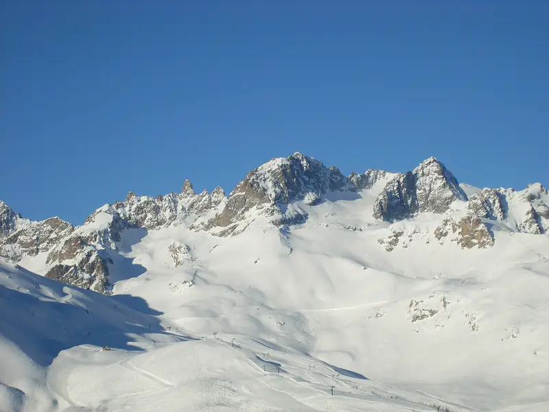 Górne stoki Serre Chevalier nad granicą lasu, skalisty grzbiet w tle