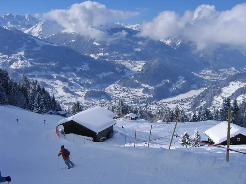 A skier on a Silvretta Montafon piste, the villages of the Montafon valley below, mountains behind