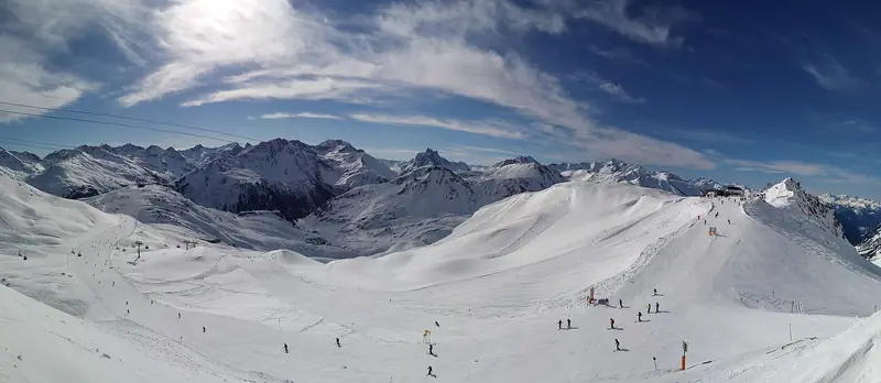 Widok z Ulmer Hütte na stoki St. Anton am Arlberg, narciarze na trasach pod schroniskiem