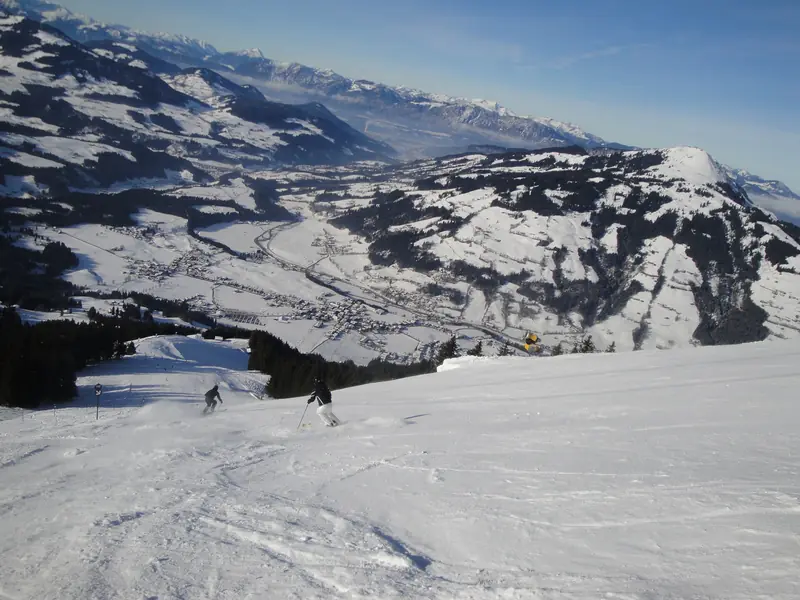 Stroma trasa w Westendorf, stok opada w dolinę, w tle ośnieżone szczyty