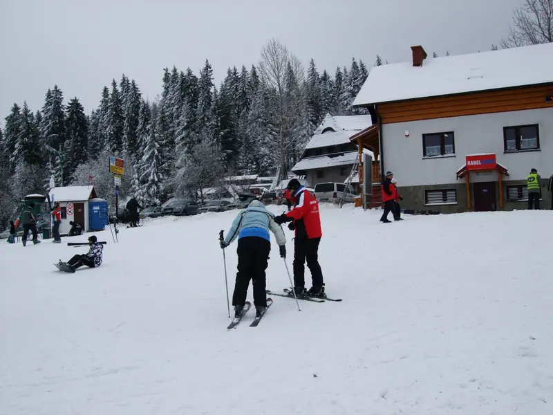 Skiers by a snow-covered guesthouse at the foot of the slope in Szczyrk