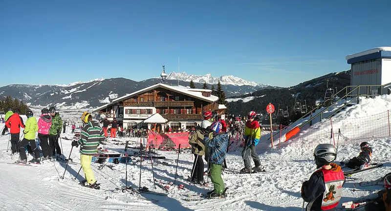 Skiers at the snowy Flachau base, a lodge and a lift