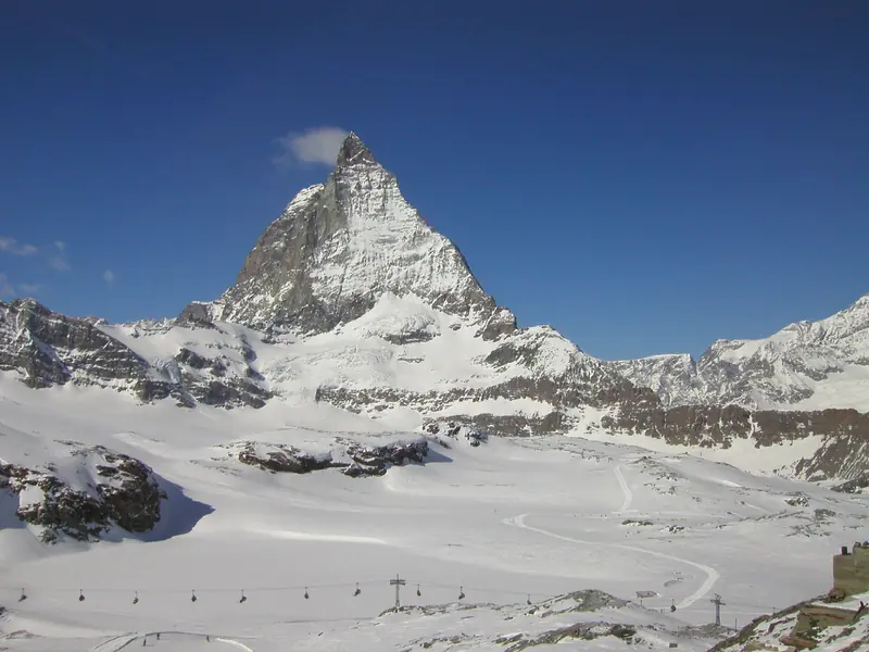 Matterhorn nad trasami Zermatt, wyciągi i narciarze na ośnieżonym stoku