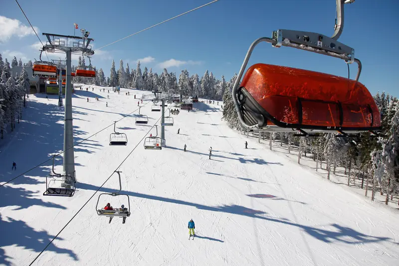 A chairlift above the snowy piste of Zieleniec Ski Arena, a skier below