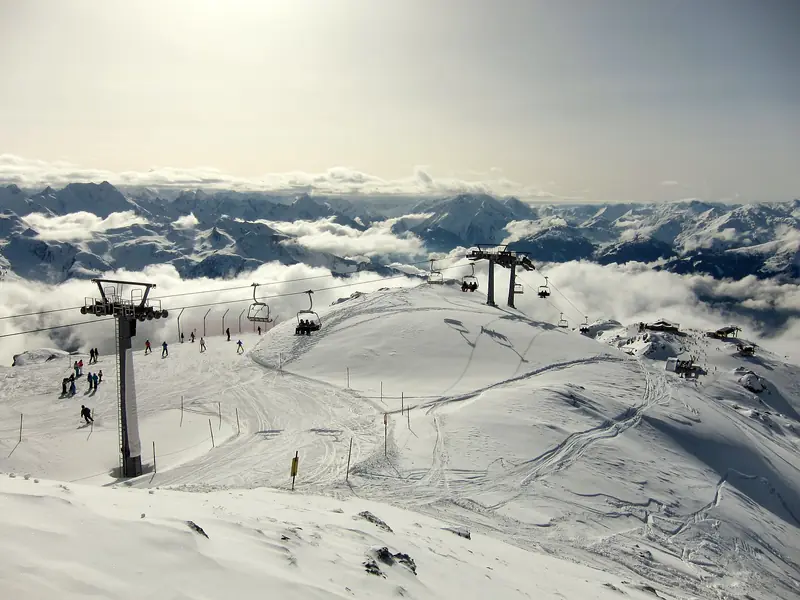 The broad Zillertal Arena ski fields with chairlift lines, a sea of cloud and distant peaks below